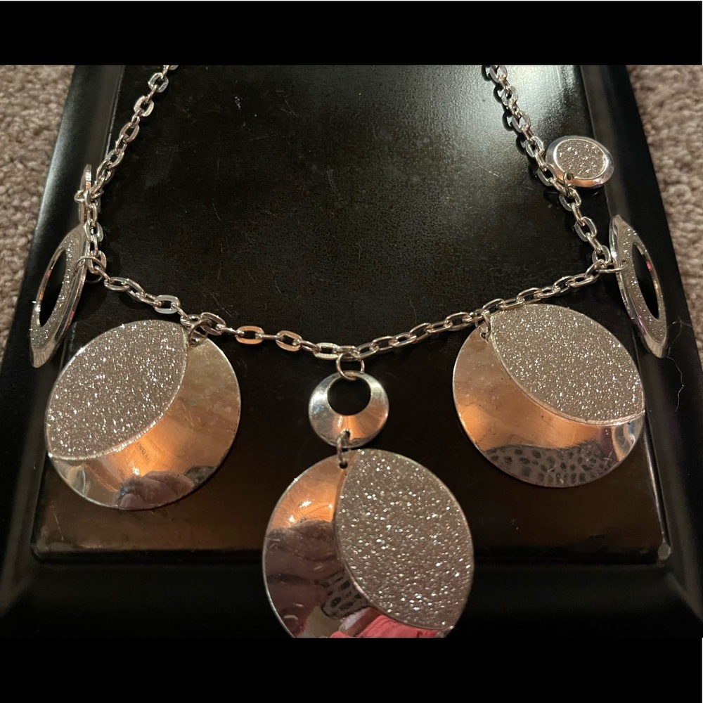 New silver tone necklace that has solid circles with sparkles.